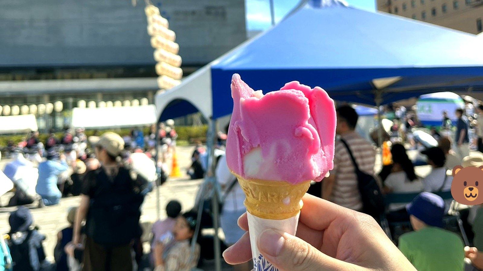 青空の下で手に持ったピンクのバラ型アイス
