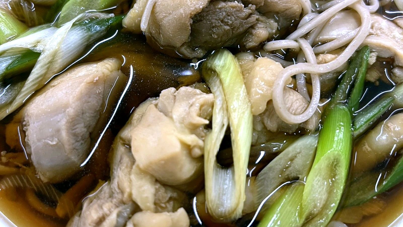 鶏肉とネギが乗った温かい蕎麦のアップ