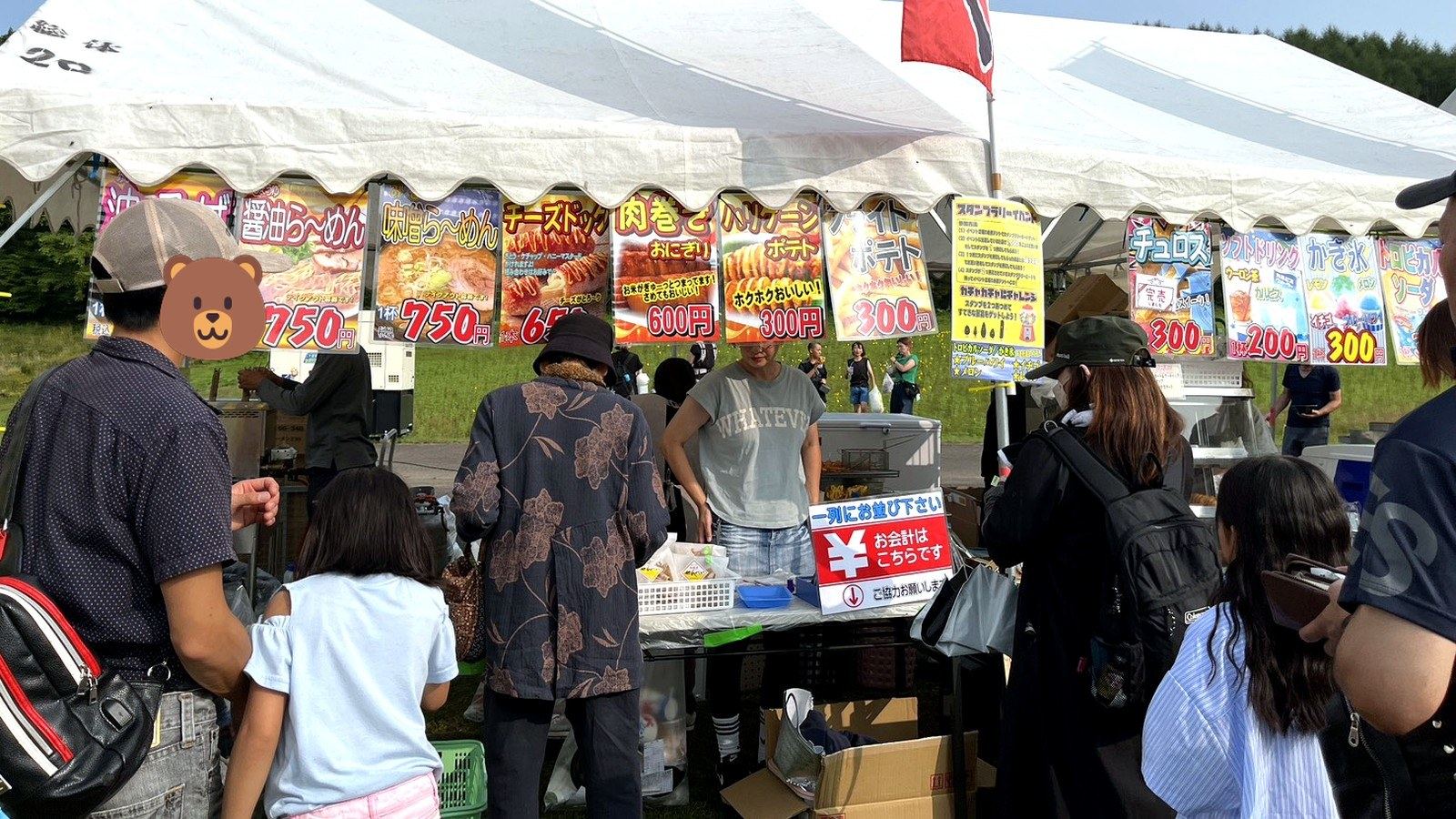 屋外イベントの屋台テントと並ぶ人々