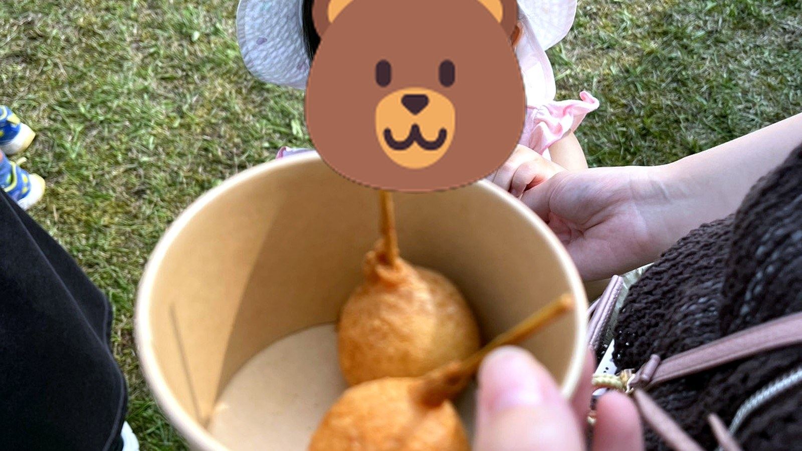 屋外でアメリカンドッグを食べる子ども