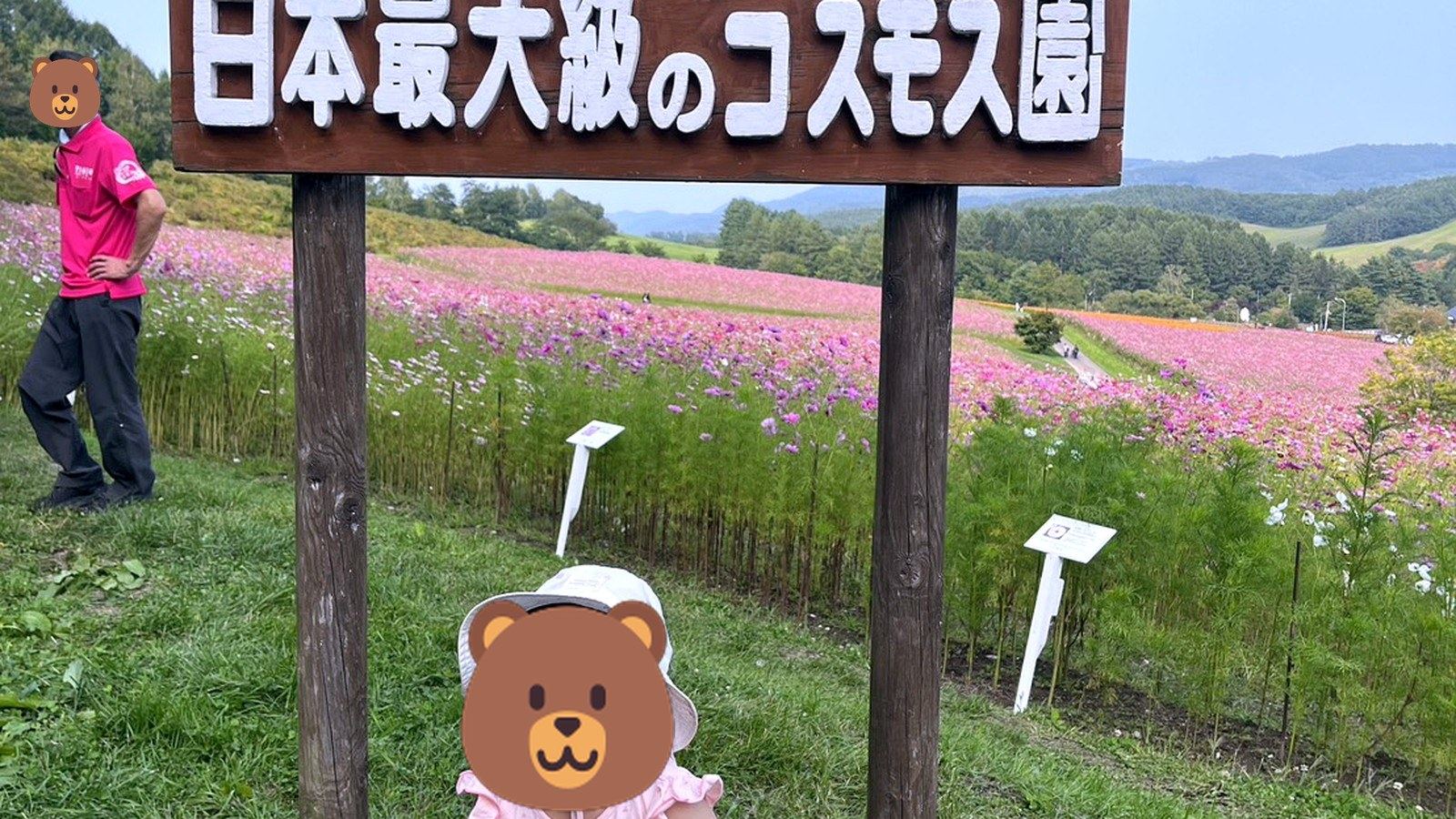えんがるコスモス園の看板前で座る子ども