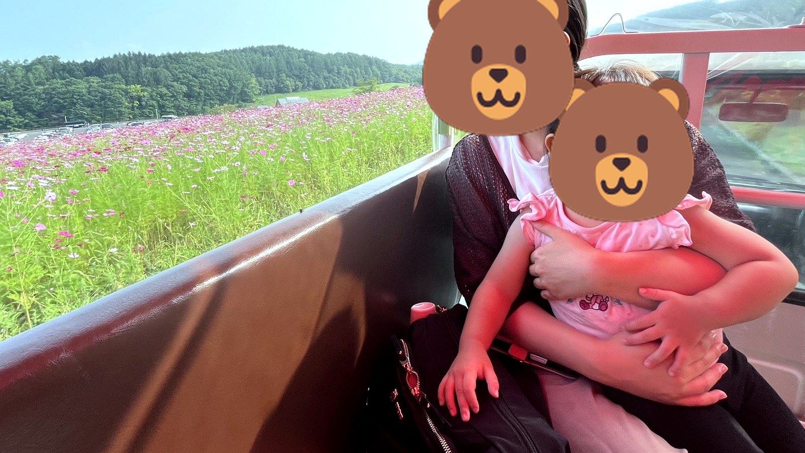 花畑を走る乗り物に乗る母と子ども