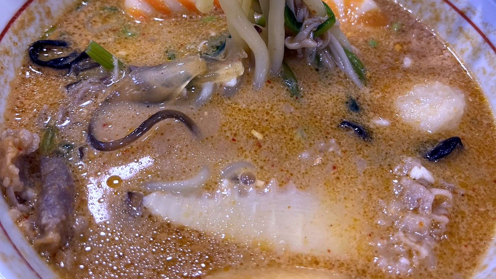 箸で麺を持ち上げた具だくさん麻辣湯