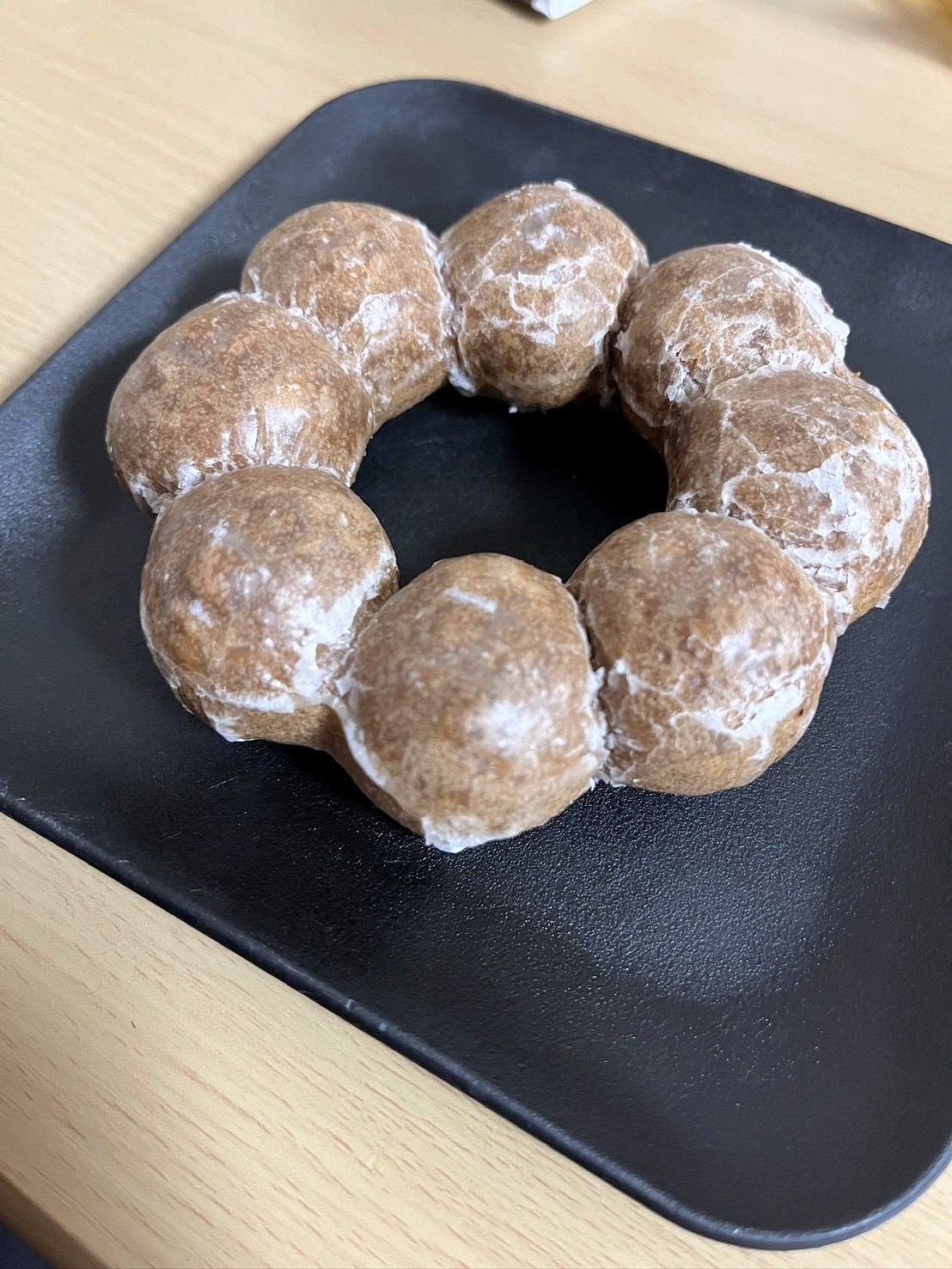 黒い四角い皿に載ったポン・デ・リング風ドーナツ