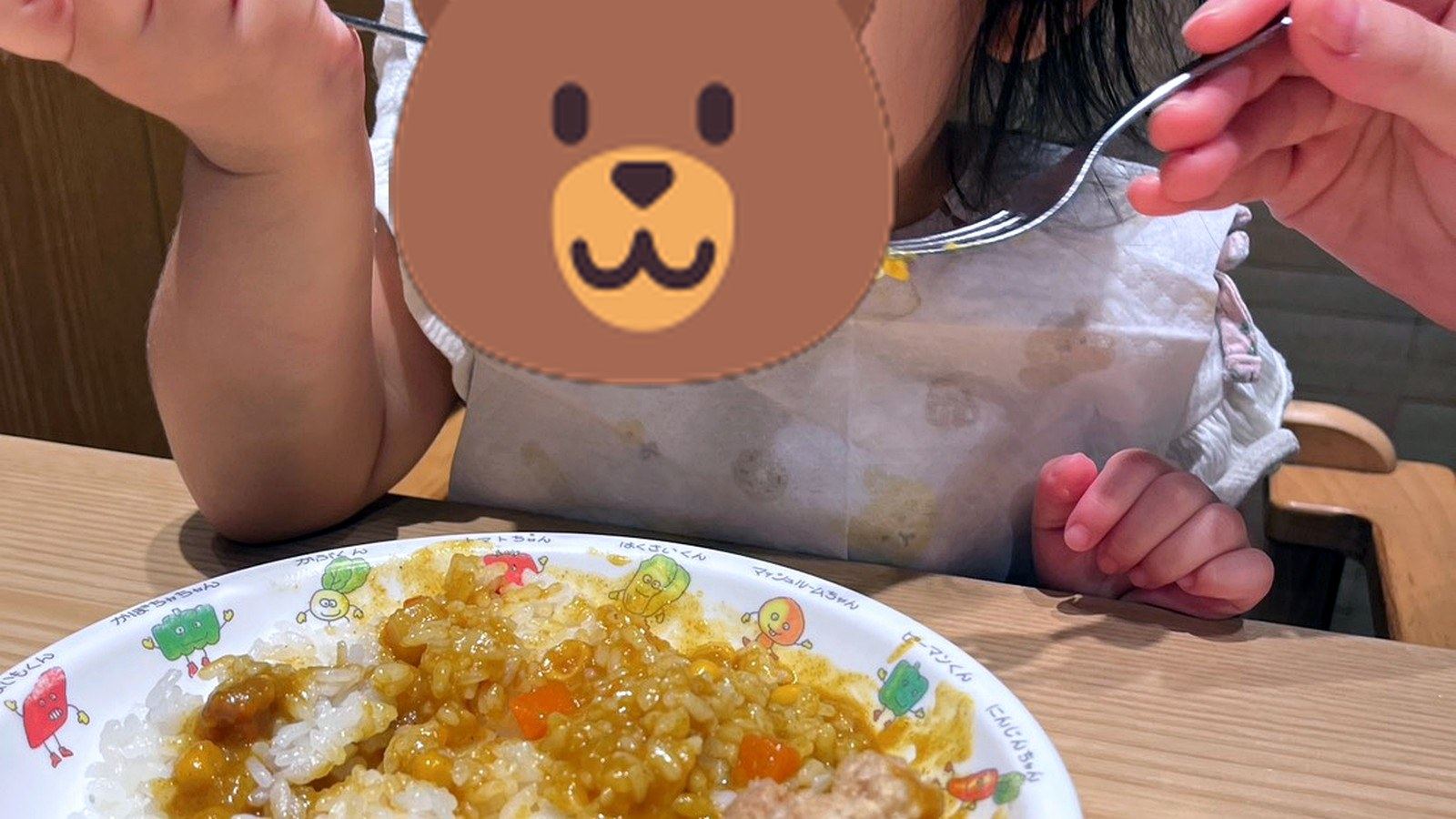 お子様カレーをスプーンで食べる小さな子ども
