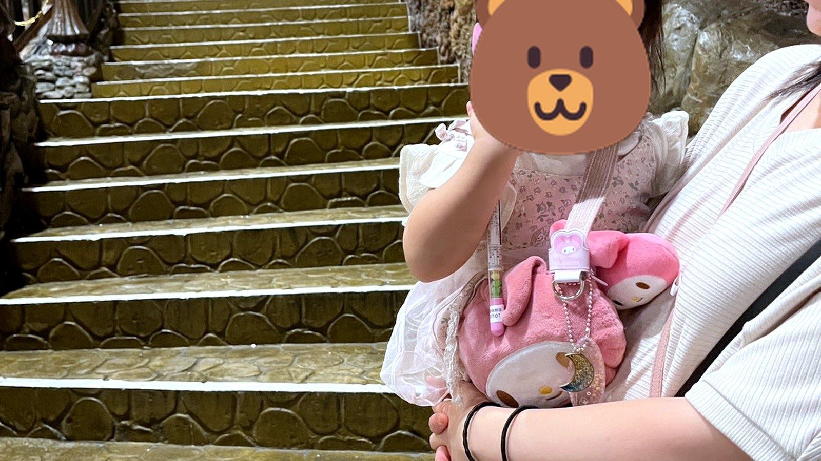 テーマパークの階段前で抱っこされて微笑む女の子