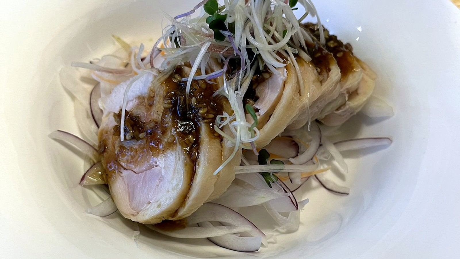 白皿に盛られた蒸し鶏のタレがけ