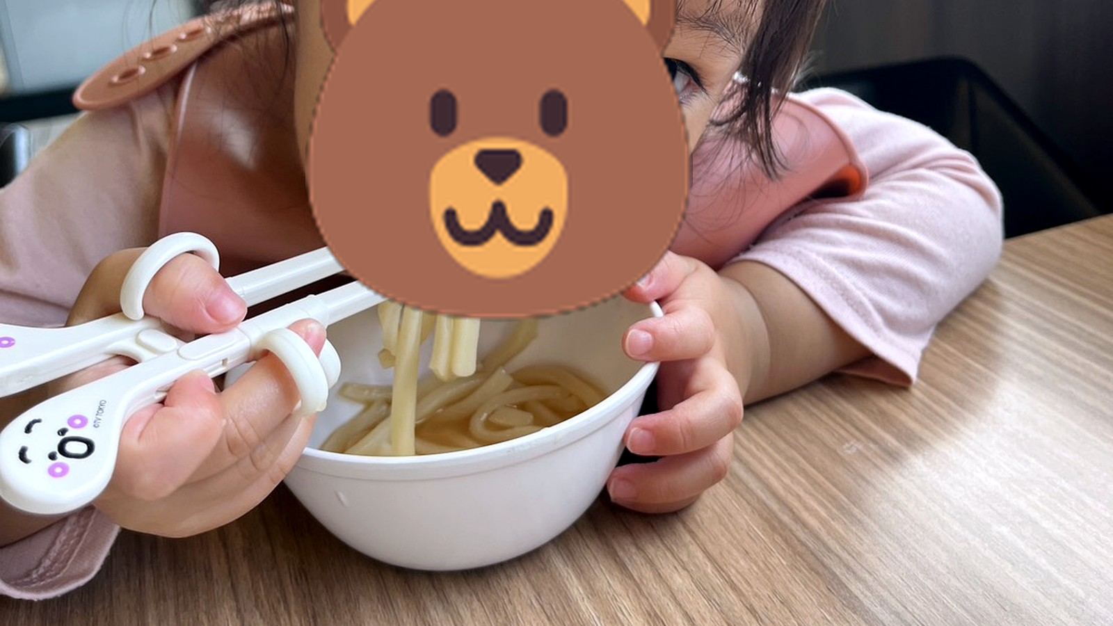 補助箸を使ってうどんを食べる小さな子ども