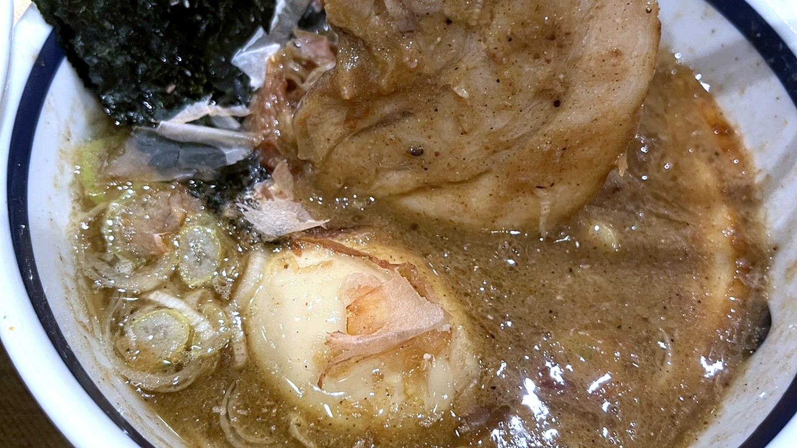 箸で持ち上げた大きなチャーシューと濃厚ラーメン
