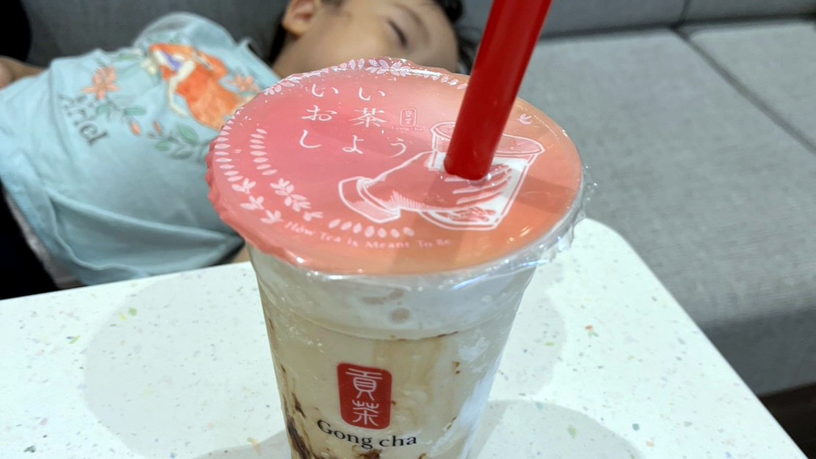 ゴンチャのドリンクと背後で眠る子ども