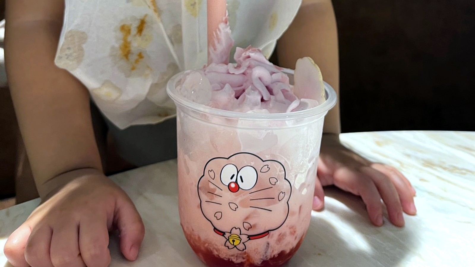 ストローでピンクのドリンクを飲む女の子
